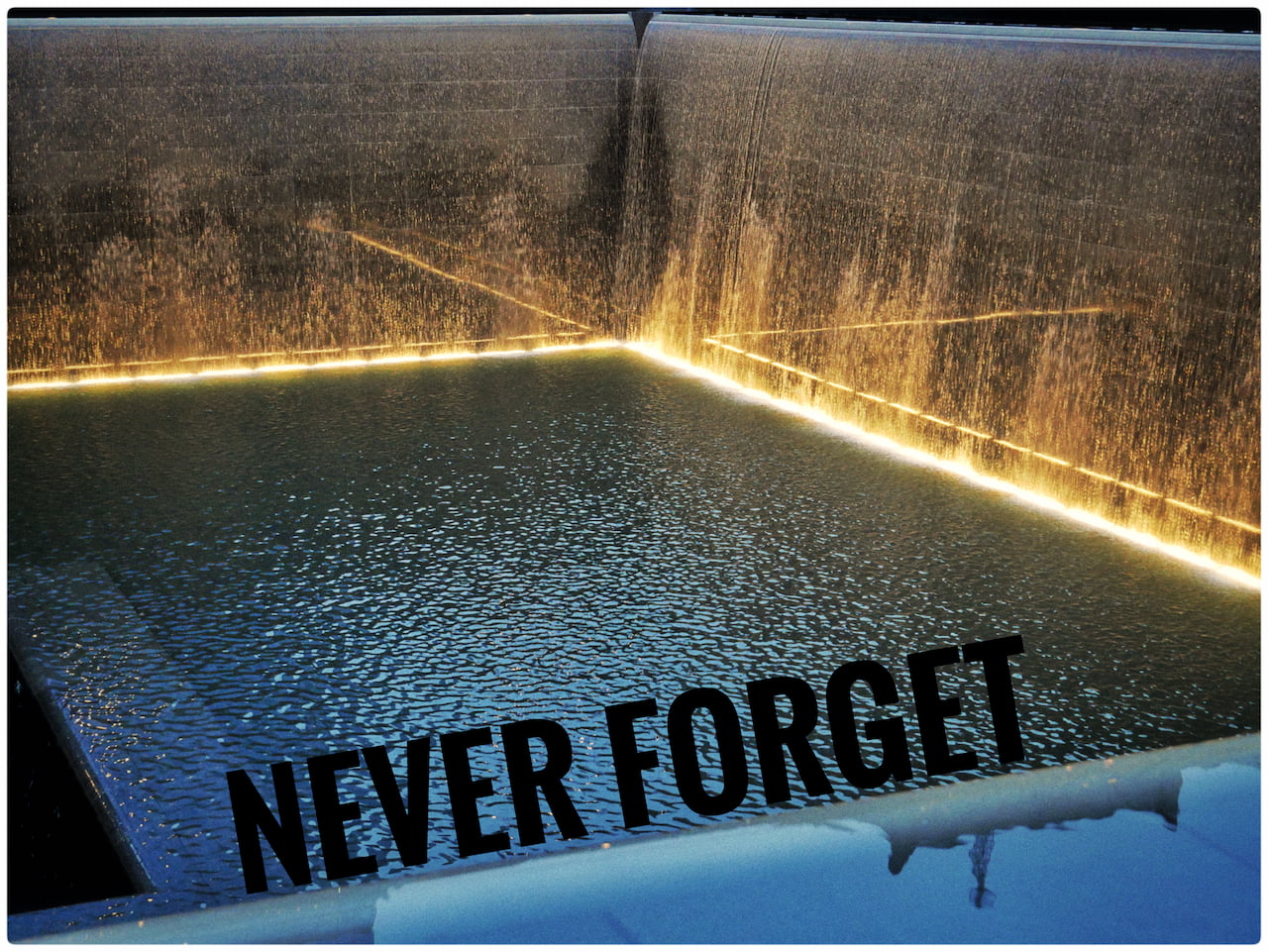 The Reflecting Pools — Einer der zwei Pools, die an der Stelle in den Boden eingelassen worden sind, an der die Twin-Towers vor ihrem Einsturz standen. Diese gehören als Mahnmal zum im Frühjahr 2014 eröffneten „9/11 Memorial”. In schwarzer Schrift ist digital „NEVER FORGET” an einem der Poolränder aufgebracht worden.